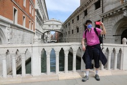 young tourist takes a selfie with the bridge of sighs in Venice, taking advantage of the lack of people due to the lockdown caused by the Coronavirus