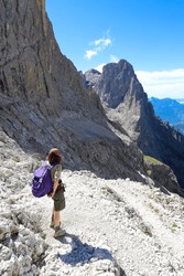 Young female hiker on trail in the middle of the European alps in Northern Italy in summer