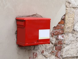 old red mailbox on the peeling wall