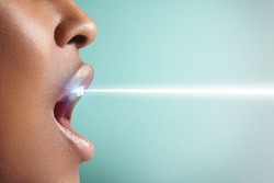 woman;s mouth is open and ray of laser is whitening her teeth