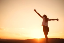 Woman open arms under the sunset. Concept of healthy life.