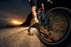 Cyclist riding mountain bike on trail at night.