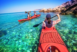 Two men paddle a kayak on the sea. Kayaking on island