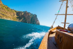 Wooden yacht. Vintage boat floating near the shore of a mountain. Fishing in the sea.