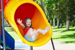 Kids climbing and sliding on outdoor playground. Children play in sunny summer park. Activity and amusement center in kindergarten or school yard. Child on colorful slide. Toddler kid outdoors.