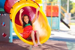 Kids on playground. Children play outdoor on school yard slide. Healthy activity. Summer vacation fun. Child playing in sunny park. Kid having fun on colorful slide.