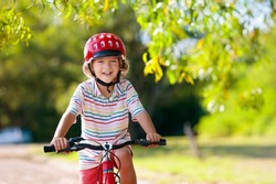 Child going to school on bike. Kids ride bicycle. Safe way to elementary school. Little boy with backpack on red bike wearing safety helmet. Healthy outdoor activity for young student.