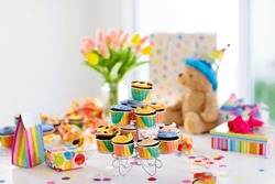 Cupcakes for kids birthday celebration. Jungle animals theme children party. Decorated room for boy or girl kid birthday. Table setting with presents, gift boxes, confetti and sweets. Pastry for child