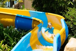Kids on water slide in aqua park. Children having fun on water slides on family summer vacation in tropical resort. Amusement park with wet playground for young child and baby.