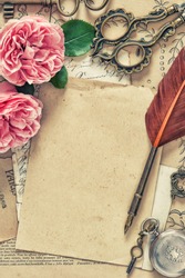 Used paper, antique feather pen, rose flowers. Vintage style toned picture