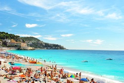 View of the beach in Nice, France, near the Promenade des Anglais. tourists, sunbeds and umbrellas on summer hot day