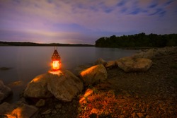Blue Springs Lake located outside of Kansas City, Missouri at night with a lantern glowing light onto the rocky shoreline