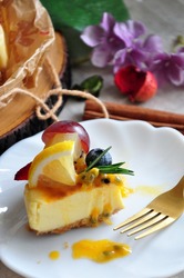 Close up A Piece of New York Cheesecake Topping with Summer Fruits and Passion Fruit Sauce on white dish 