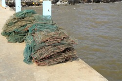 Pile of Folding net for catching crayfish and crabs on jetty floor against the sea. Old crab trap or catcher boxes for a crab catcher on the concrete floor.
