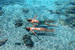 Happy couple swimming in the transparent turquoise sea. Tropical vacation and honeymoon concept. Top view of 