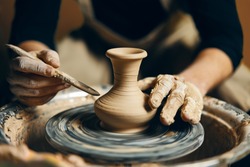 Man potter working on potters wheel making ceramic pot from clay in pottery workshop. art concept