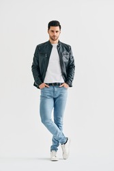 Handsome stylish man portrait on white studio background. Men's beauty concept. Young male wearing jeans, white t-shirt and black leather jacket posing full length