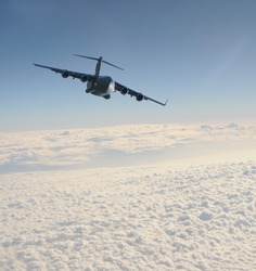 heavy military transport jet above the clouds
