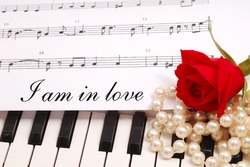 red silky rose with musical notes and a piano