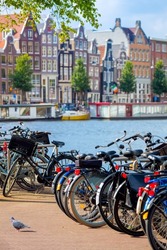 Famous view of Amsterdam - parked bicycles and traditional houses on the Amstel river. Amsterdam, Holland, Netherlands, Europe