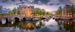 Amsterdam. Panoramic view of the downtown of Amsterdam. Traditional houses and bridges of Amsterdam. A blue evening time and the serene reflection of lights in the water. Long exposure.  Holland