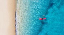 Kayaking. Sup. Aerial view of floating board and people on blue sea at sunny day. Summer seascape. Landscape from drone. Travel and active life image. 