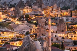 Goreme, Cappadocia, Turkey. View of the evening city from the mountain. Bright evening city. Landscape in the summertime. UNESCO heritage. Vacation and tourism.