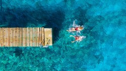 A carefree couple jumps into the azure sea. Aerial view. Young and energetic people dive into the water together. A fun vacation at the sea together.