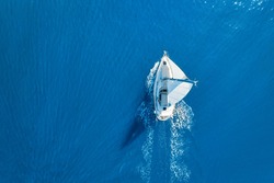 Wave and sail yacht on the sea as a background. Sea and waves from top view. Blue water background from top view. Top view from drone. Summertime vacation. Travel image