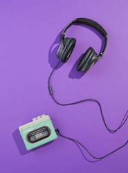 Flat lay composition with cassette player and headphones on purple background. Minimalist retro style and 80s music.