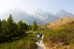 family of two, father and son, hiking and enjoying the gorgeous views in grand teton national parl, wyoming, during fall, active family vacation concept