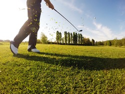 Golfer performs a golf shot from the fairway.