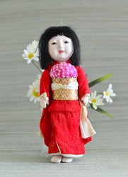 Japanese geisha doll with dark hair in a dress.