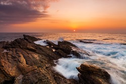 Sunset on the rocky shore of a tropical island