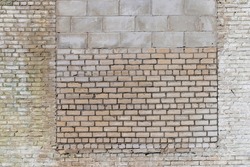 an old brick wall made of a large number of different types of bricks, part of an old building that has been repaired and redone many times