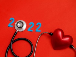 Wooden colorful on text 2022 banner for health care and Red heart love medical concept. black stethoscope,on table red background.