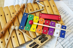 Some typical, colorful music instruments as used mostly by children. The musical score in the background is in the Public Domain. 