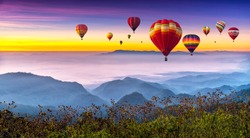 Colorful hot air balloons flying above high mountain at sunrise with beautiful sky background