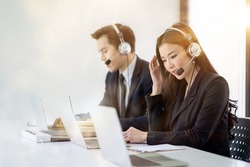 Young female operator agent with headsets and her team working in a call centre customer service office. Asian employee woman working with a headset.