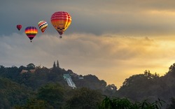 Hot air balloons flying over Wat Phra That Doi Suthep Temple with misty fog and sunlight, National Park in Chiang Mai Province, Thailand