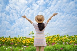 Young asian positive woman raising hands with joy and inspiration facing the white cloud and blue sky in the morning