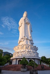 White Lady Buddha at Linh Ung Pagoda in Danang (Da Nang), Vietnam. Majestic white Buddha statue on blue sky background. Giant white standing lady Buddha statue in Chùa Linh Ứng Buddhist temple