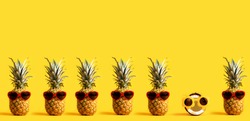 Series of pineapples and a coconut wearing sunglasses on a yellow background
