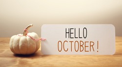Hello October message with a white small pumpkin