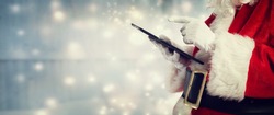 Santa Claus using a tablet in snowy night