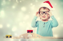 Happy toddler girl with a Santa hat and glasses playing with her toys