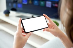female hands holding horizontally phone with isolated screen on the background of TV in the room