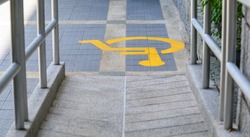 Yellow painted handicapped sign traffic symbol on the floor in front of ramp way for support wheelchair