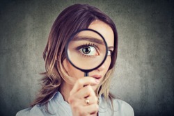 Curious young woman looking through a magnifying glass 