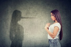 Side view of a woman pointing at herself looking at a shadow with long nose of a liar.